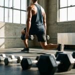 Fitness enthusiast traint met halters in moderne sportschool met natuurlijk licht door grote ramen